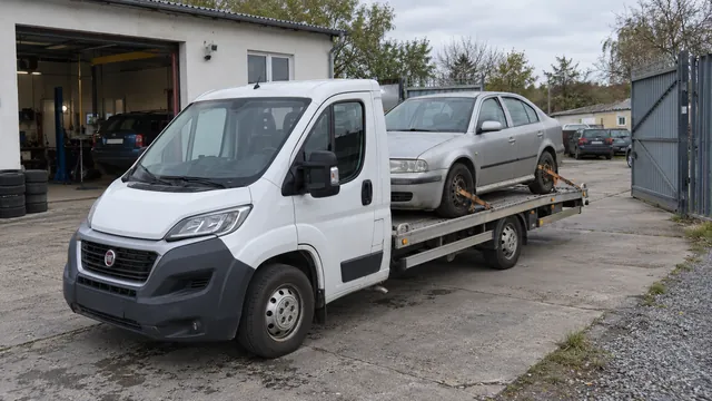 Bílý odtahový vůz s upevněným vozidlem Škoda na hliníkové plošině