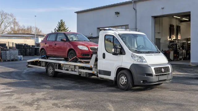 Bílý odtahový vůz s upevněným vozidlem Škoda na hliníkové plošině