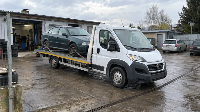 Bílý odtahový vůz s upevněným vozidlem Škoda na hliníkové plošině