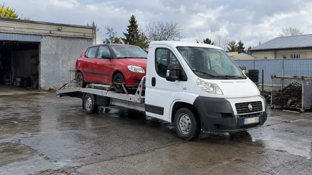 Bílý odtahový vůz s upevněným vozidlem Škoda na hliníkové plošině