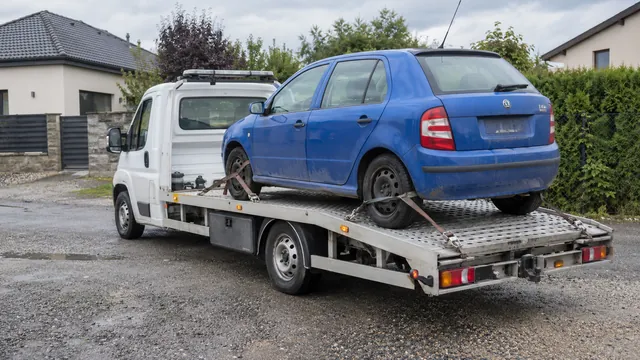 Bílý odtahový vůz s upevněným vozidlem Škoda na hliníkové plošině