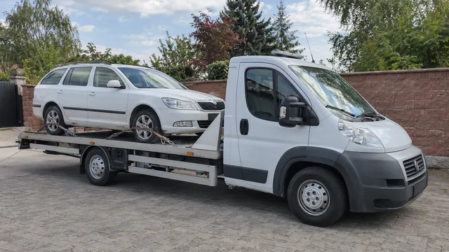 Bílý odtahový vůz s upevněným vozidlem Škoda na hliníkové plošině