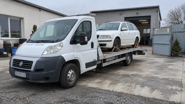 Bílý odtahový vůz s upevněným vozidlem Škoda na hliníkové plošině