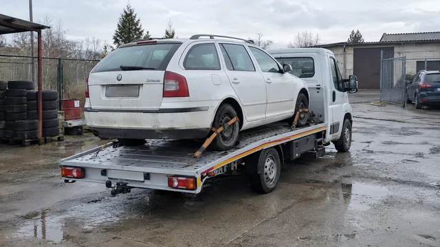 Bílý odtahový vůz s upevněným vozidlem Škoda na hliníkové plošině