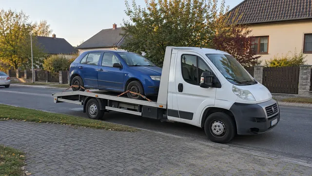 Bílý odtahový vůz s upevněným vozidlem Škoda na hliníkové plošině
