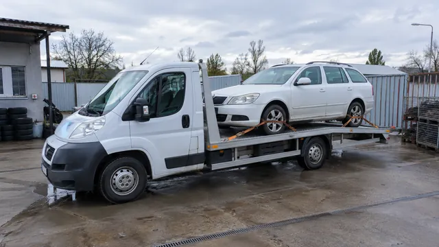 Bílý odtahový vůz s upevněným vozidlem Škoda na hliníkové plošině